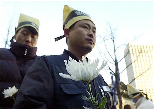 14일 오후 대한상공회의소앞 인도에 마련된 고 배달호씨의 분향소에 헌화하기 위해 민주노총 조합원들이 국회꽃 한송이를 들고 서 있다. 